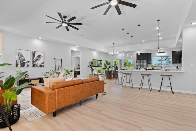 living room with ceiling fan with notable chandelier and light wood-type flooring