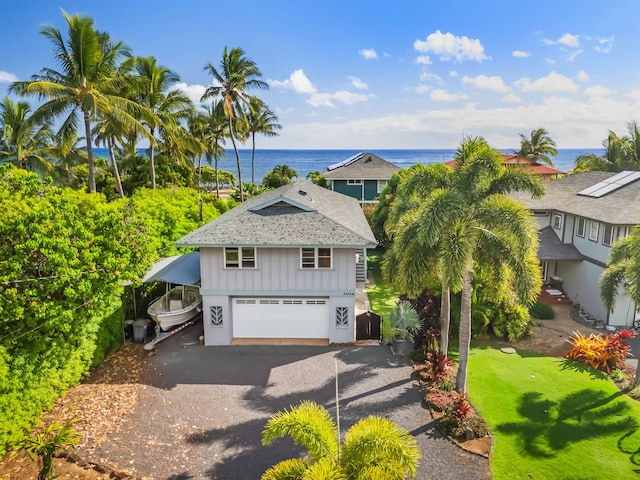 beach home with a front lawn, a garage, and a water view