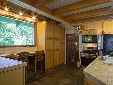 kitchen featuring appliances with stainless steel finishes, dark tile flooring, beam ceiling, and tile counters