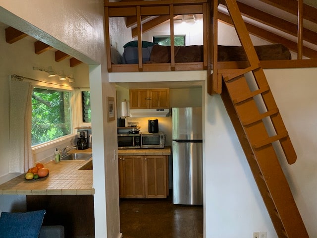 kitchen with vaulted ceiling with beams, sink, stainless steel appliances, and tile countertops