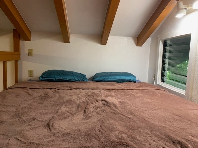 carpeted bedroom with vaulted ceiling with beams