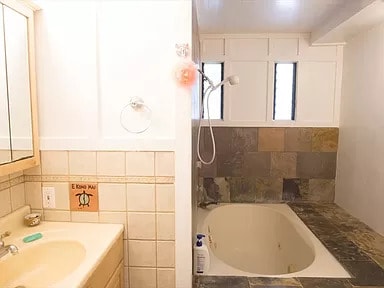 bathroom with a bath to relax in, tile walls, and vanity