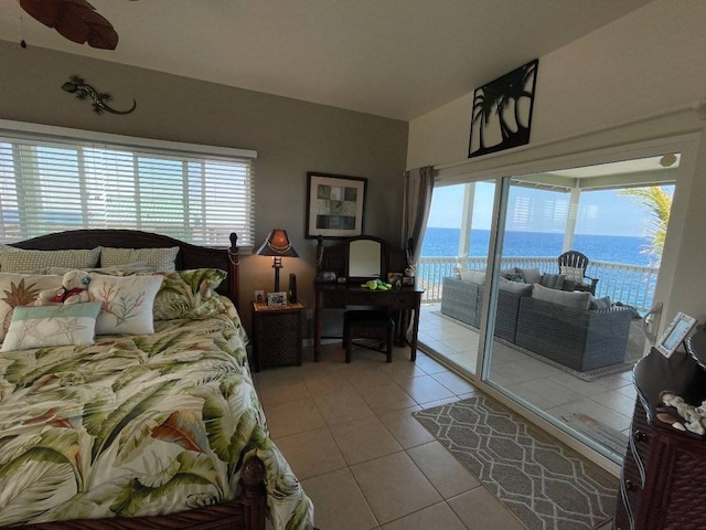 bedroom featuring multiple windows, tile floors, access to outside, and a water view