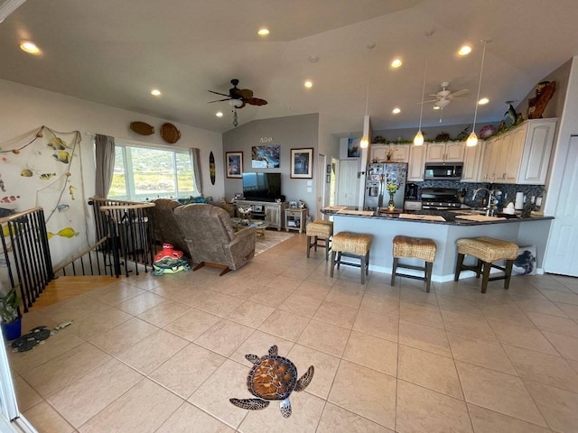 tiled living room with sink, ceiling fan, and vaulted ceiling