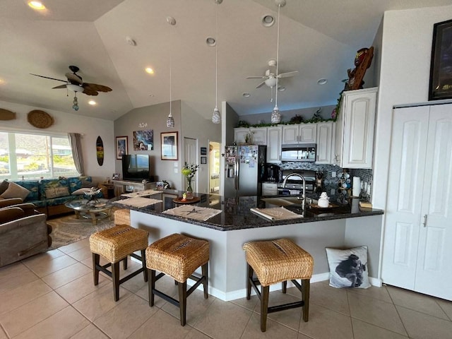 kitchen featuring a breakfast bar, white cabinets, stainless steel appliances, tasteful backsplash, and ceiling fan