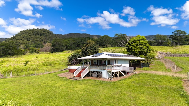 back of house with a wooden deck, a lawn, and a rural view