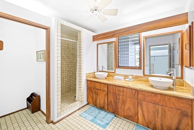 bathroom with dual sinks, ceiling fan, tile floors, vanity with extensive cabinet space, and a tile shower