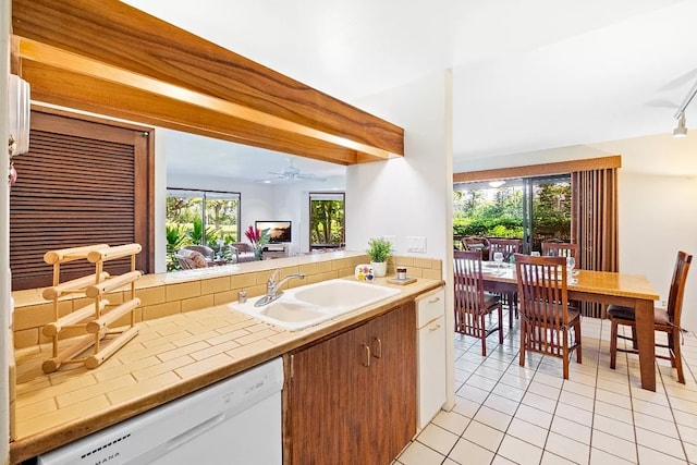 kitchen with tile counters, light tile patterned flooring, a sink, ceiling fan, and dishwasher