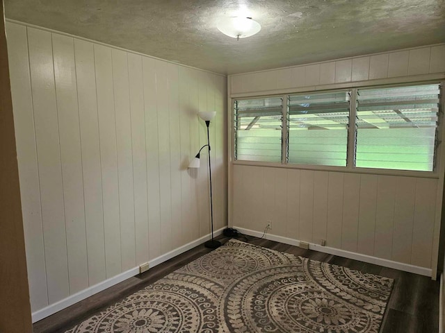 unfurnished room featuring a textured ceiling and dark wood-type flooring