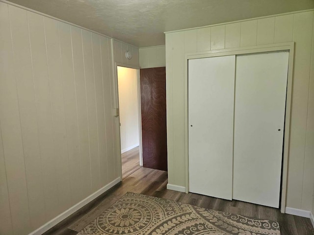 unfurnished bedroom featuring a closet, a textured ceiling, and dark hardwood / wood-style floors