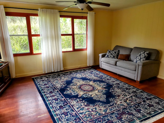 living room featuring ceiling fan, a healthy amount of sunlight, and dark wood-type flooring