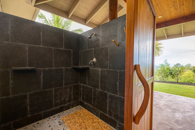 bathroom with vaulted ceiling with beams, tiled shower, and wood ceiling