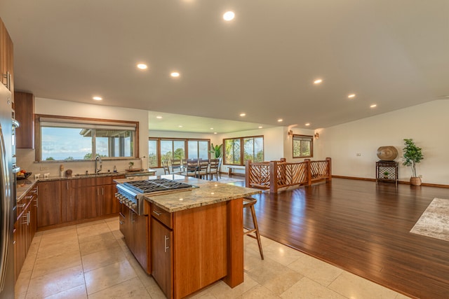 kitchen with a center island, light hardwood / wood-style floors, light stone countertops, backsplash, and sink