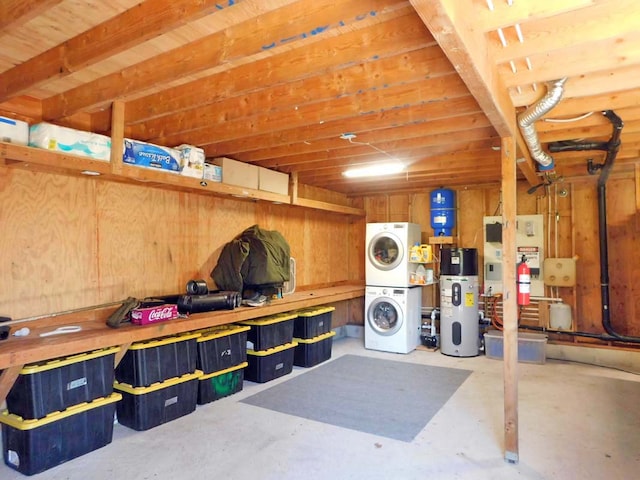 basement featuring heat pump water heater, a workshop area, and stacked washer and dryer