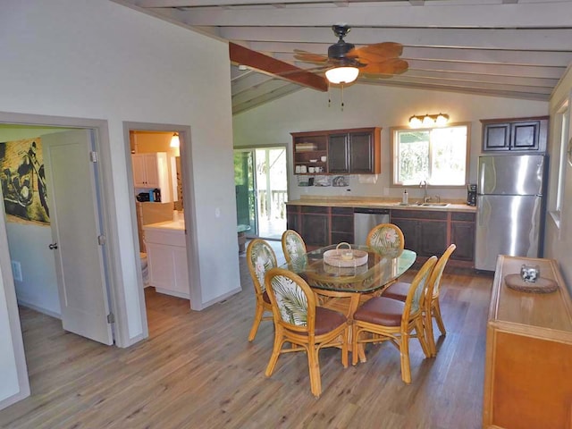 dining room featuring ceiling fan, sink, vaulted ceiling with beams, and wood-type flooring