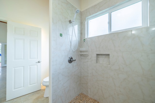 bathroom with tiled shower, crown molding, tile flooring, and toilet