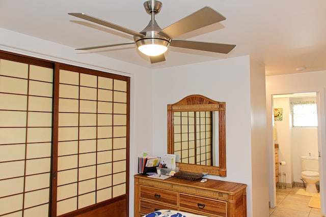 tiled bedroom featuring ensuite bath and ceiling fan