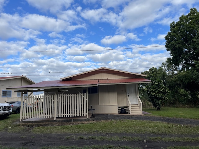 view of front of house featuring a carport, entry steps, metal roof, and a front lawn