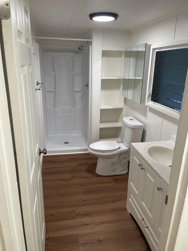 bathroom with a shower, vanity, toilet, and wood finished floors