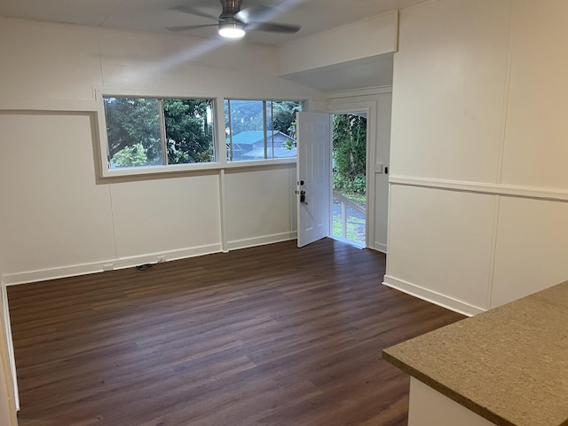 spare room with ceiling fan, a decorative wall, and dark wood-style flooring