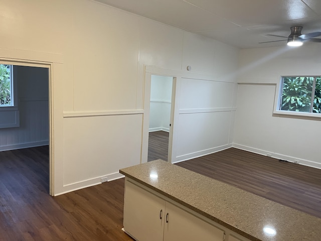 unfurnished room with a ceiling fan, a decorative wall, and dark wood-type flooring