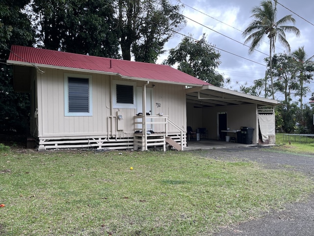 view of front of property featuring metal roof, an attached carport, a front yard, and driveway