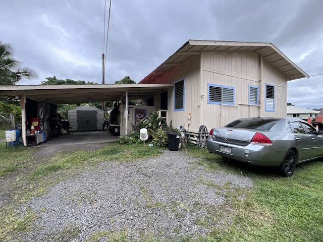 view of side of property with driveway, a shed, an outdoor structure, and an attached carport