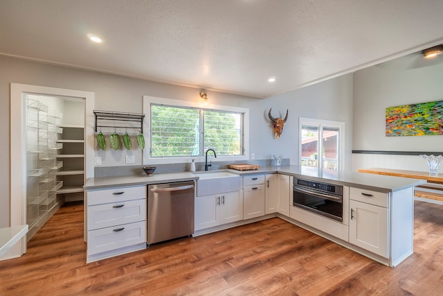 kitchen with white cabinetry, stainless steel appliances, light wood-type flooring, and sink