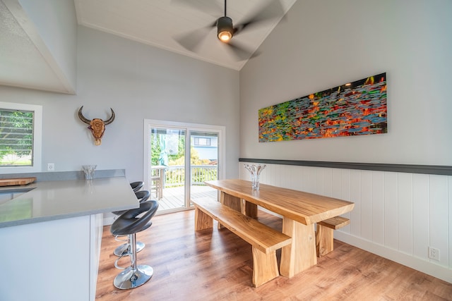 dining space featuring high vaulted ceiling, ceiling fan, and light wood-type flooring