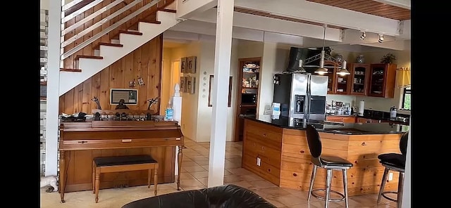 kitchen with stainless steel fridge, decorative light fixtures, rail lighting, a breakfast bar, and light tile floors