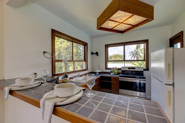 kitchen with tile countertops, electric range, a wealth of natural light, and white refrigerator