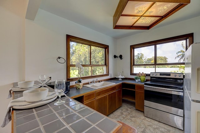 kitchen with tile counters, stainless steel electric range, white refrigerator, and sink