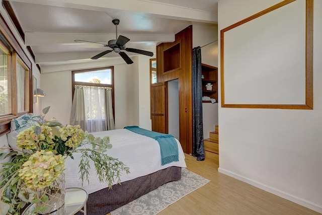 bedroom with vaulted ceiling with beams, ceiling fan, and light wood-type flooring