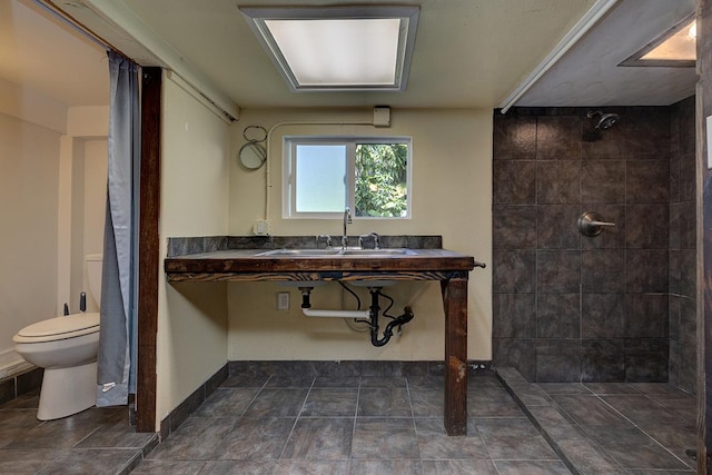 bathroom featuring tiled shower, toilet, and sink