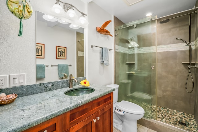 bathroom featuring tile flooring, vanity with extensive cabinet space, a shower with shower door, and toilet