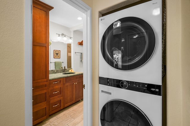 laundry area with sink, light hardwood / wood-style flooring, and stacked washer and clothes dryer