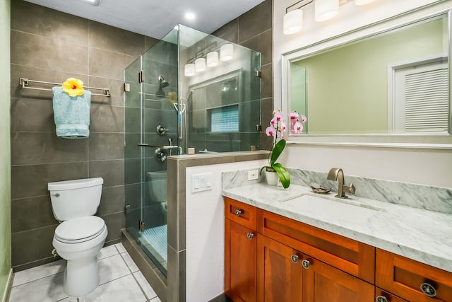 bathroom with tile flooring, tile walls, walk in shower, toilet, and vanity