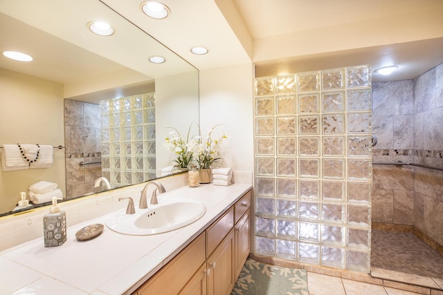 bathroom with a tile shower, vanity, and tile patterned floors