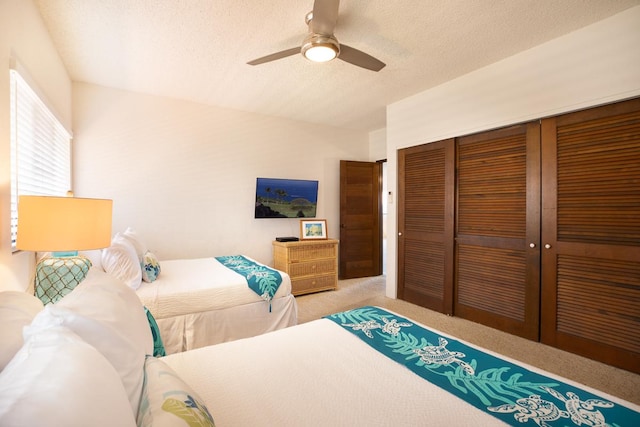 carpeted bedroom featuring ceiling fan, a textured ceiling, and a closet