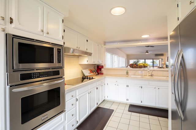 kitchen featuring backsplash, stainless steel appliances, sink, light tile patterned floors, and white cabinetry