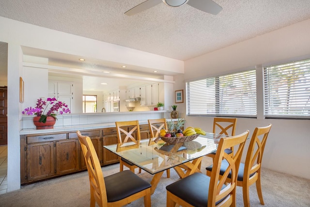 carpeted dining area with a textured ceiling and ceiling fan