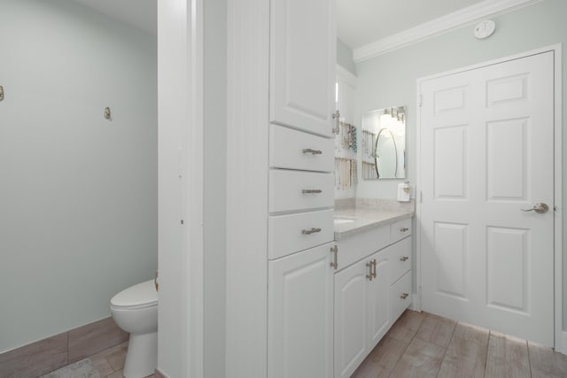 bathroom with vanity, toilet, and ornamental molding