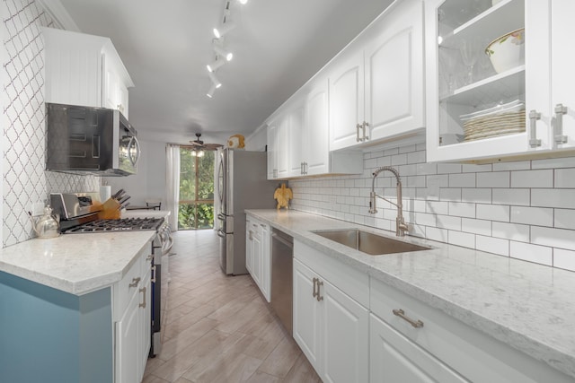 kitchen with light stone countertops, sink, white cabinets, and stainless steel appliances