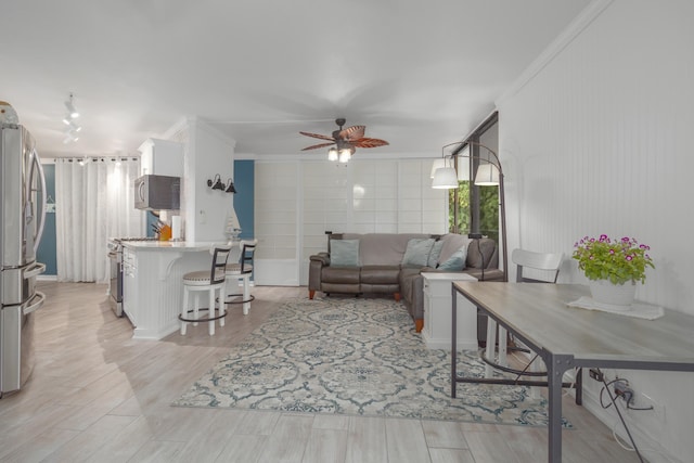 living room with light wood-type flooring, ceiling fan, and ornamental molding