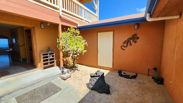 doorway to property with a balcony and stucco siding