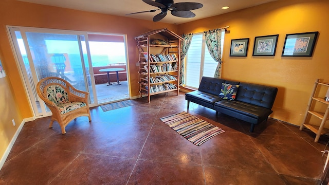 living area featuring concrete flooring, ceiling fan, a wealth of natural light, and baseboards