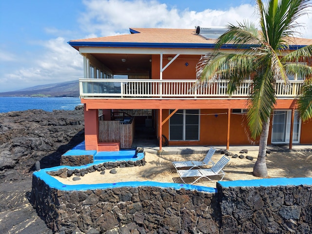 back of property with a patio area, a water and mountain view, and roof with shingles