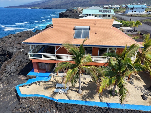 exterior space featuring a balcony, a water and mountain view, and a tiled roof