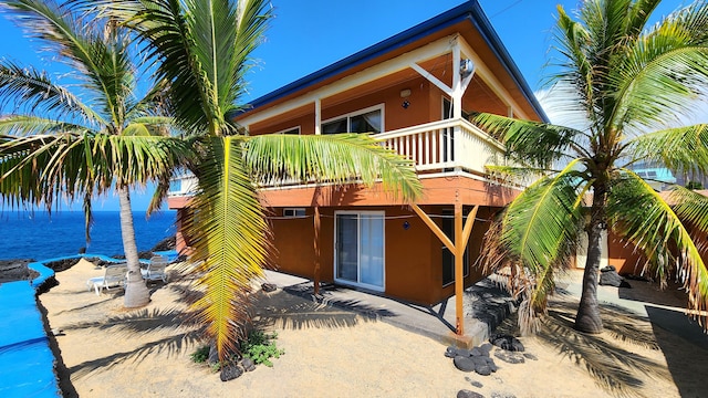 back of house featuring a water view and stucco siding