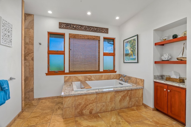 bathroom featuring tile flooring, tiled tub, and vanity